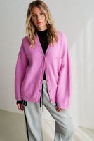 Frau trägt pinken Cardigan über schwarzem Top mit grauen Jogginghosen, lässiger Look.