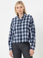 Frau trägt oversized kariertes Hemd mit dunkelblauen und hellen Streifen, schwarze Jeans.