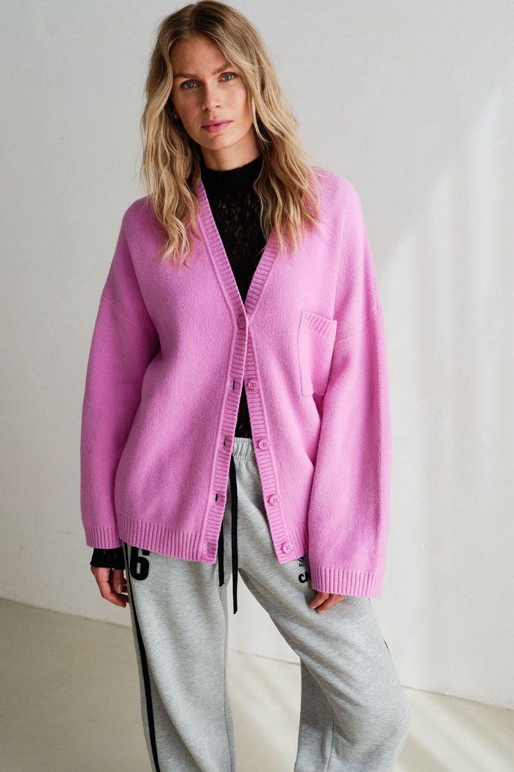 Frau trägt pinken Cardigan über schwarzem Top mit grauen Jogginghosen, lässiger Look.