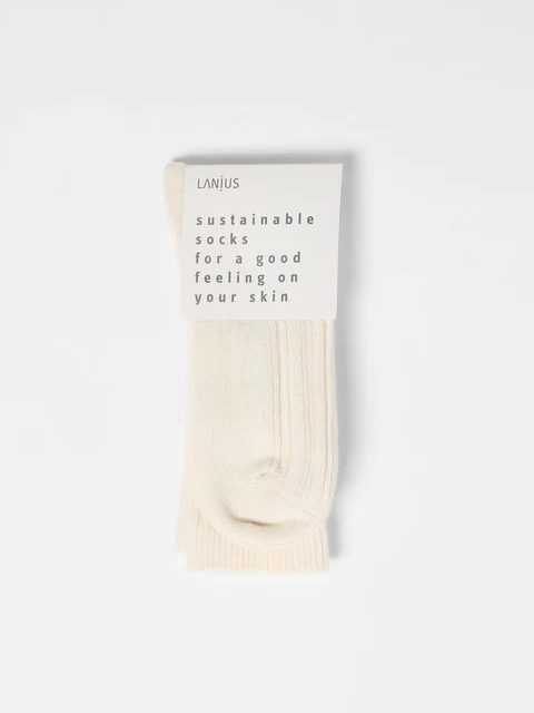 Weiße nachhaltige Socken von Lanius mit Hautpflege-Versprechen im Verpackungskarton.