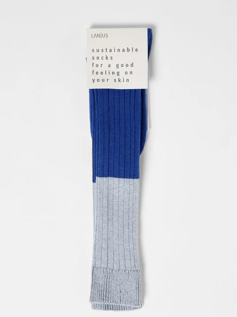 Blau-graue Socken mit nachhaltiger Beschreibung in Zellstoffverpackung.