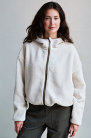 Frau trägt cremefarbenen, flauschigen Hoodie mit Zipfel und dunkle, weite Jeans.