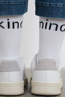 Weiße Socken mit „kind mind“ und weiße Sneakers, unter Jeans getragen.