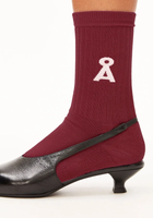 Maroon-Strumpfhose mit weißem Ribbon-A-Symbol, kombiniert mit schwarzem Pumpschuh.
