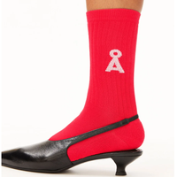 Rote Strumpfhose mit weißem Schleifensymbol, kombiniert mit schwarzem Pumpschuh.
